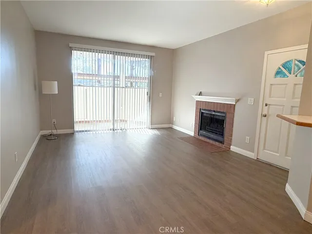 an empty room with wooden floor fireplace and windows