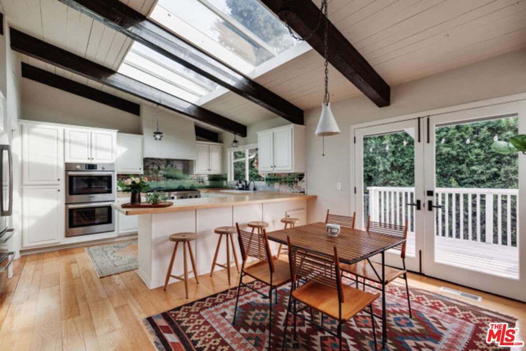 3629 Serra Road Malibu, CA 90265 - Photo 2 of 18 a kitchen with stainless steel appliances granite countertop a stove top oven a sink dishwasher a dining table and chairs with wooden floor