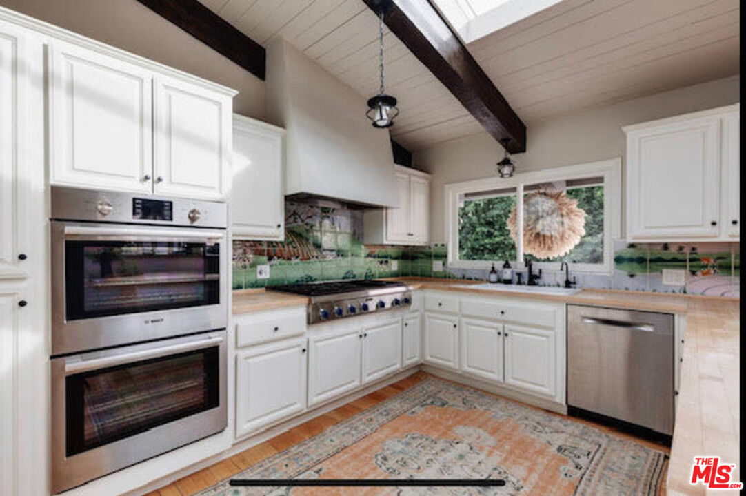 3629 Serra Road Malibu, CA 90265 - Photo 3 of 18 a kitchen with cabinets wooden floor and stainless steel appliances