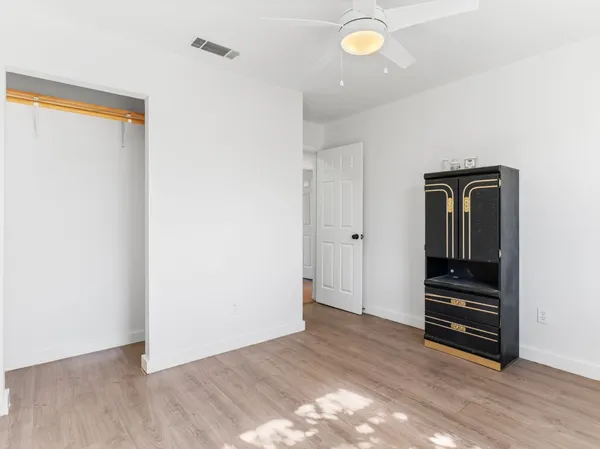a view of an empty room with wooden floor and closet