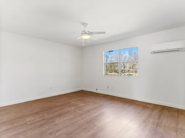 an empty room with wooden floor and ceiling fan