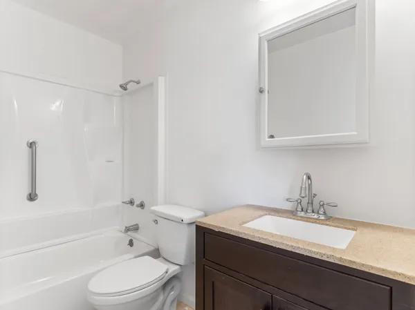 a bathroom with a granite countertop sink toilet a mirror and shower