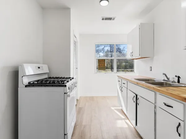 a kitchen with granite countertop a sink stove and refrigerator