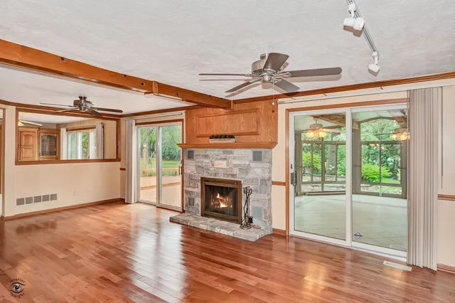 a view of a room with wooden floor fireplace and windows