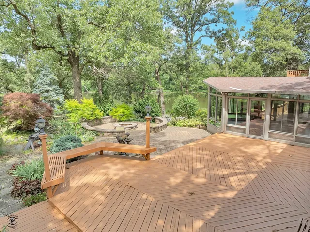 a view of a patio with table and chairs under an umbrella with large trees