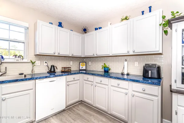 a kitchen with granite countertop white cabinets white appliances and a sink