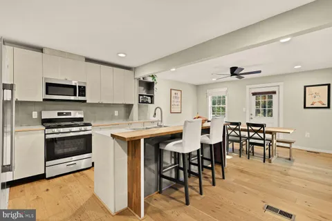 a kitchen with stainless steel appliances granite countertop a stove top oven a sink dishwasher a dining table and chairs with wooden floor