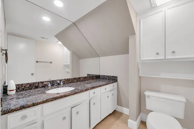 a bathroom with a granite countertop sink a toilet and a mirror