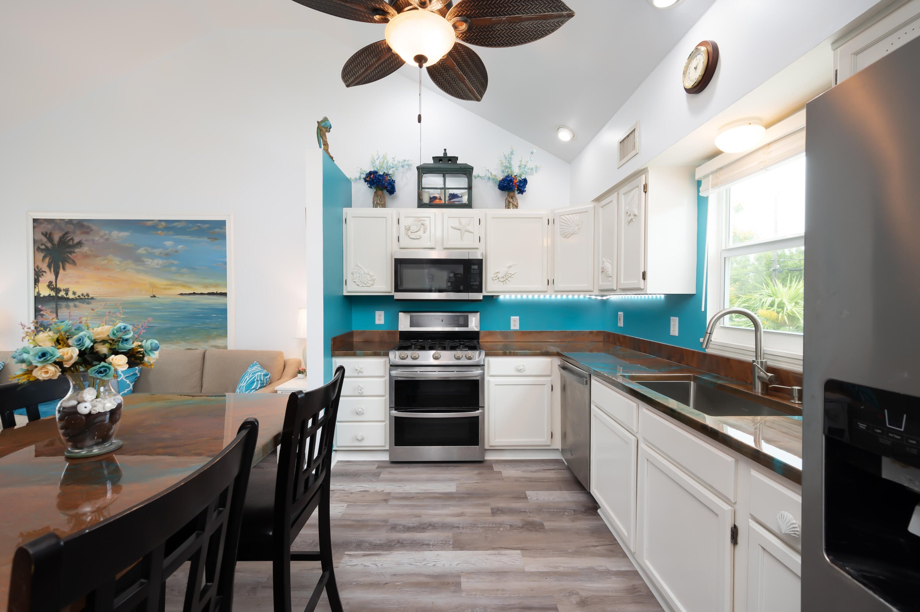 29072 Cedar Drive Big Pine Key, FL 33043 - Photo 9 of 59 a kitchen with stainless steel appliances granite countertop a stove top oven a sink a dining table and chairs with wooden floor