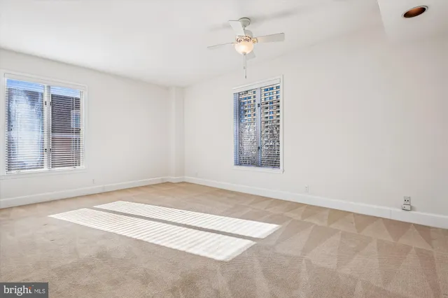 an empty room with windows and fan