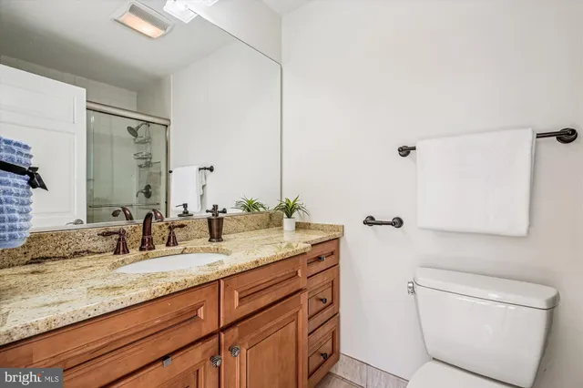 a bathroom with a granite countertop sink a toilet and a mirror