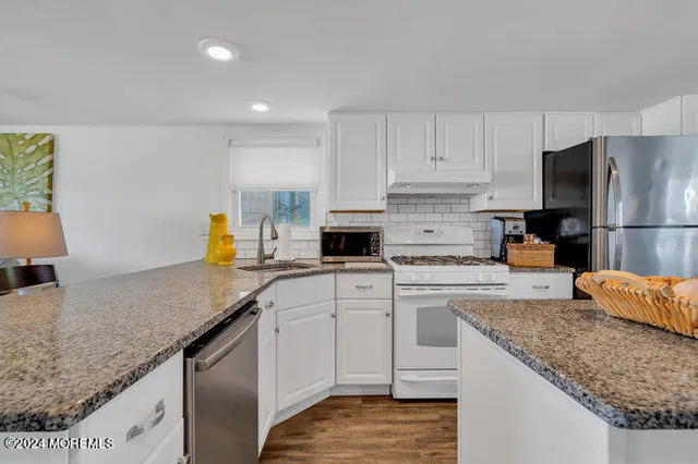 a kitchen with granite countertop a sink a counter top space appliances and cabinets