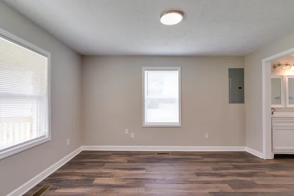 an empty room with wooden floor and windows