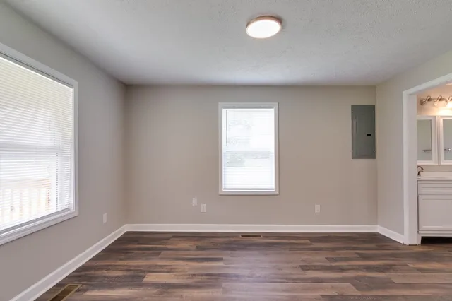 an empty room with wooden floor and windows