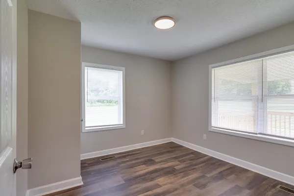 an empty room with wooden floor and windows