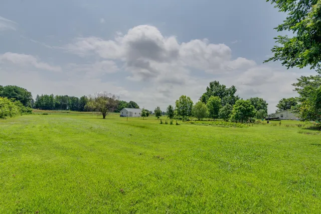 a view of a green field with wooden fence