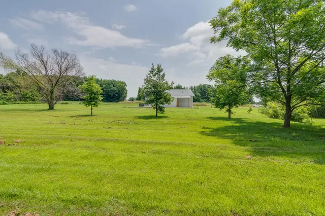 a view of a house with a big yard and palm trees