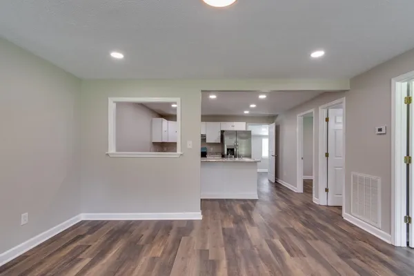 a kitchen with stainless steel appliances granite countertop a refrigerator a sink dishwasher a stove and white countertops with wooden floor