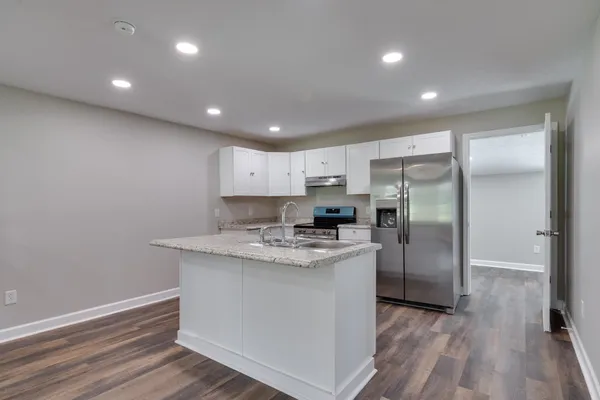 a kitchen with stainless steel appliances granite countertop a sink refrigerator and cabinets