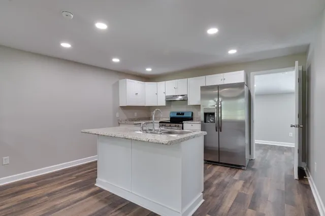 a kitchen with stainless steel appliances granite countertop a sink refrigerator and cabinets