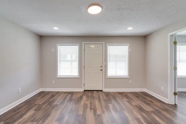 an empty room with wooden floor and windows
