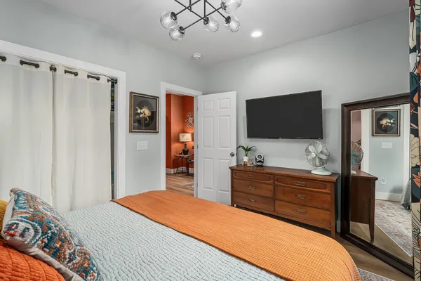 a bedroom with a bed and a flat tv screen on dresser