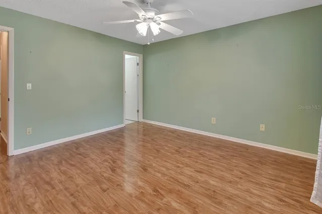 an empty room with wooden floor and fan