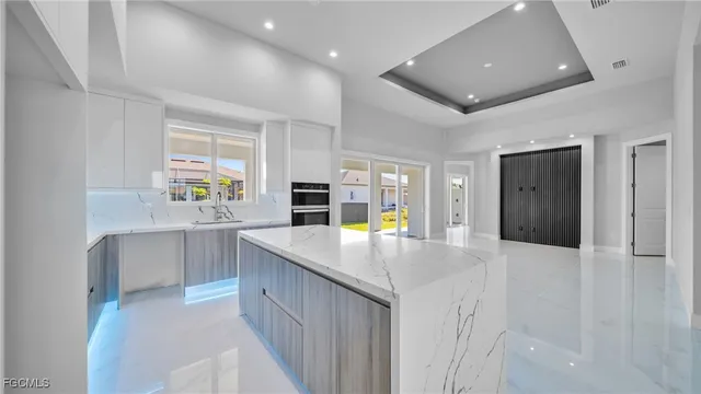 a kitchen with kitchen island a counter top space a sink a refrigerator and a stove