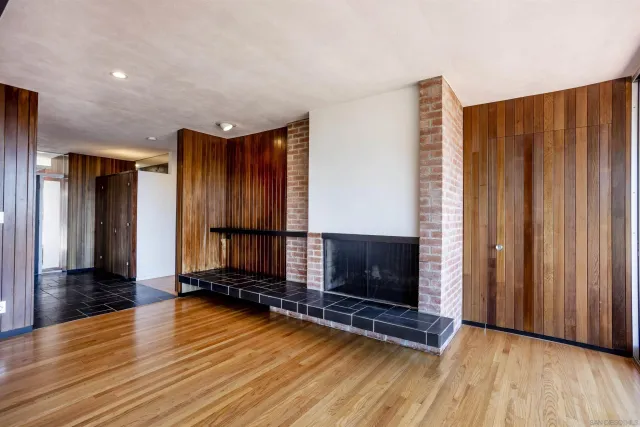 a view of an empty room with wooden floor and a fireplace