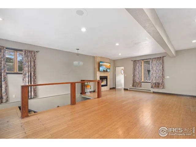 a view of an empty room with window and wooden floor