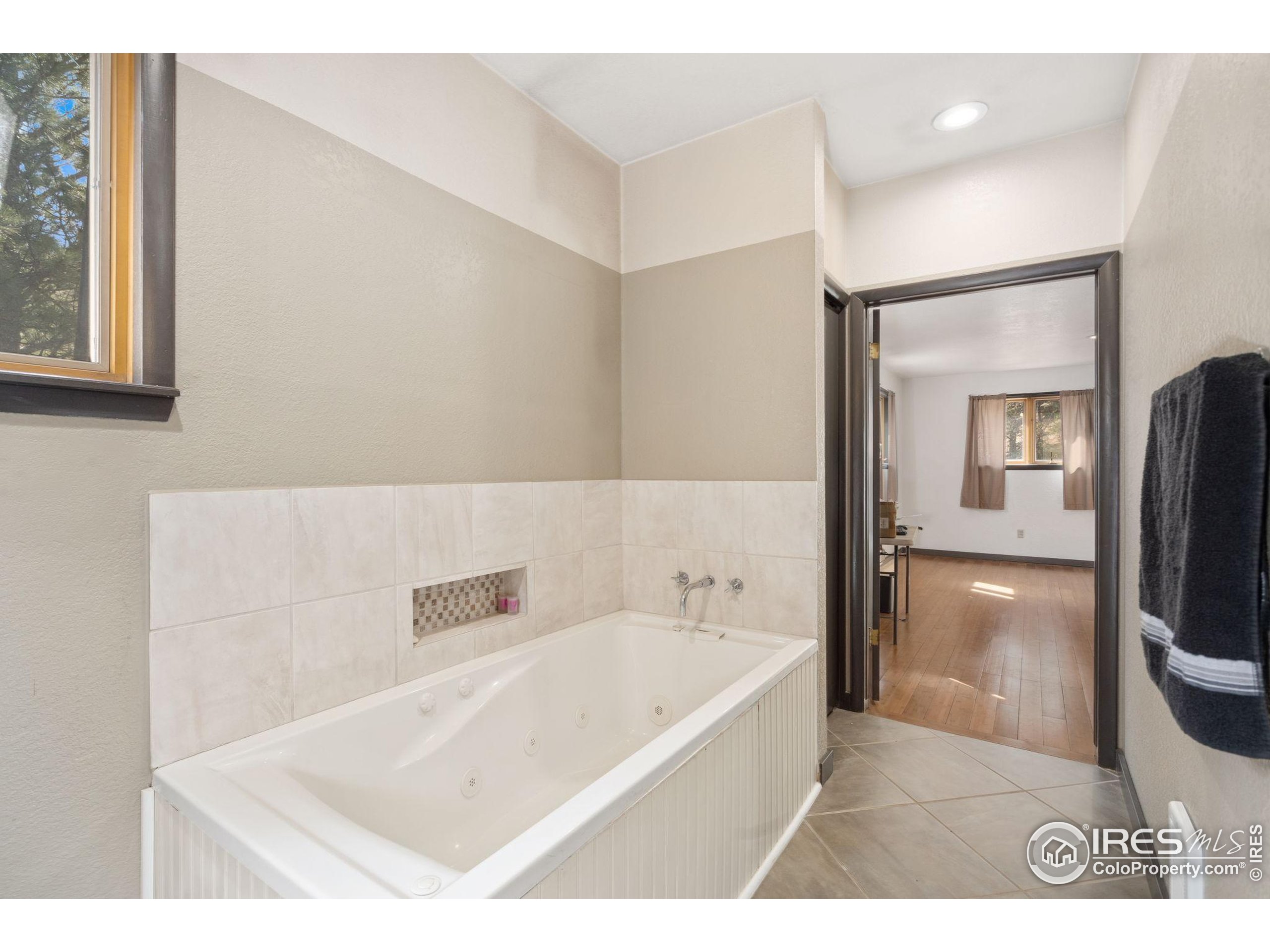 7301 Poudre Canyon Road Bellvue, CO 80512 - Photo 16 of 41 a bathroom with a tub a sink and a large mirror