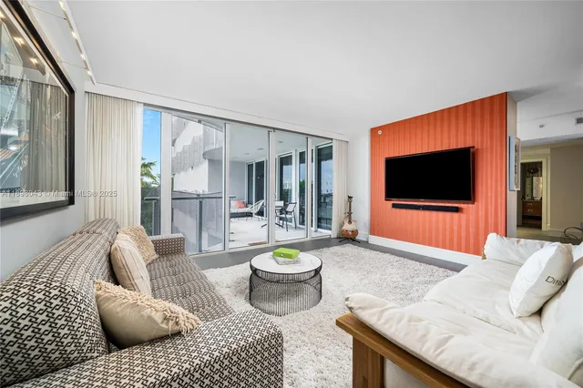 a living room with furniture a flat screen tv and a floor to ceiling window