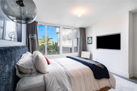 a bedroom with a large bed and a flat tv screen on dresser