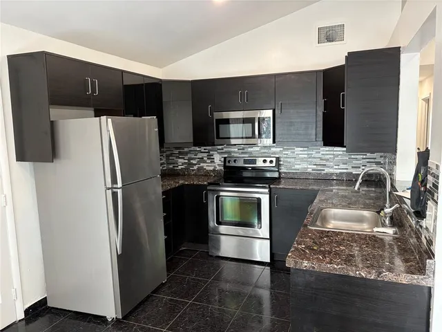 a kitchen with stainless steel appliances granite countertop a refrigerator stove and sink
