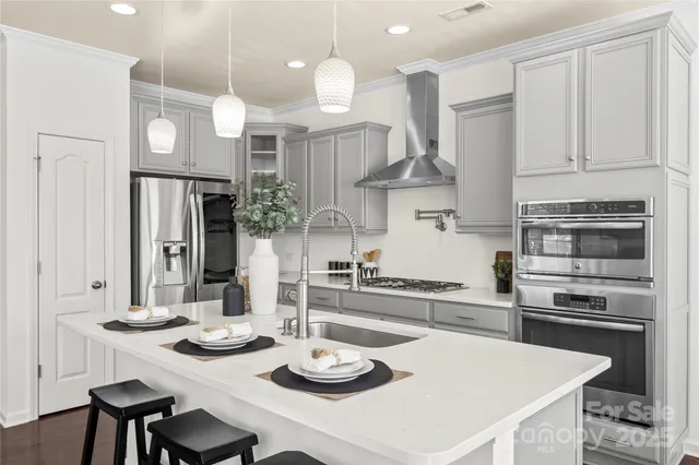 a kitchen with stainless steel appliances granite countertop a sink a stove and chairs