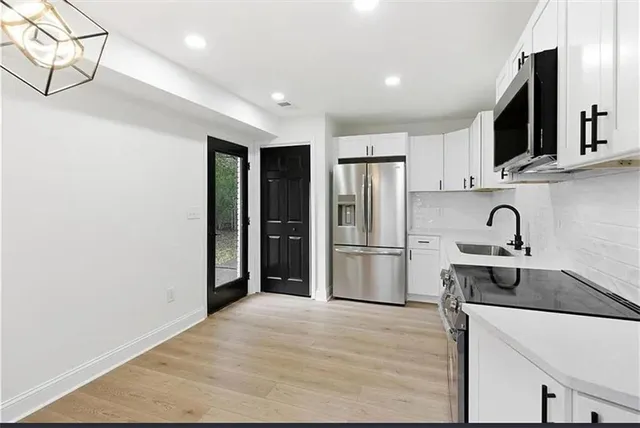 a kitchen with stainless steel appliances granite countertop a refrigerator sink and white cabinets