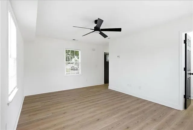 a view of empty room with wooden floor and fan