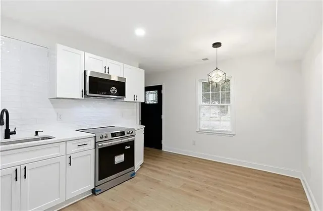 a kitchen with stainless steel appliances a stove a sink and a microwave