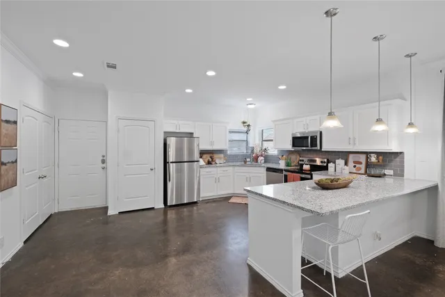 a large kitchen with stainless steel appliances kitchen island granite countertop a stove top oven a sink and dishwasher