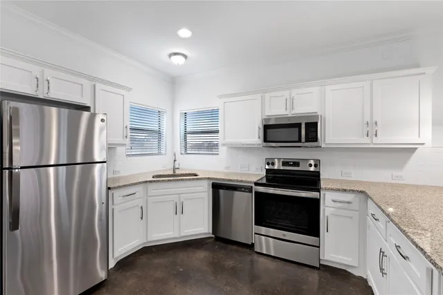 a kitchen with sink a microwave a stove and cabinets