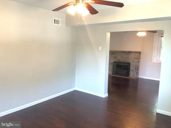 an empty room with wooden floor fireplace and windows