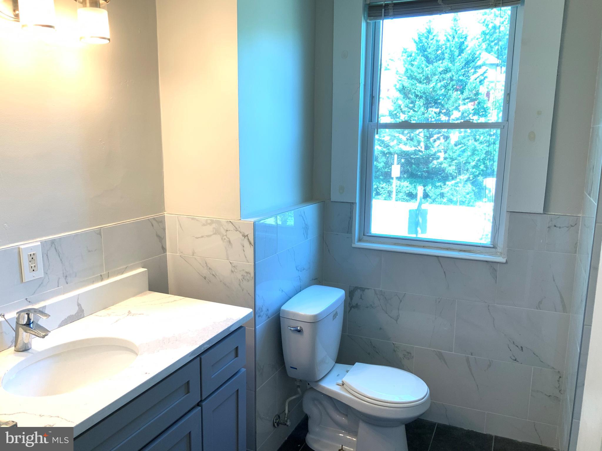 6209 York Road, Unit A Baltimore, MD 21212 - Photo 15 of 31 a bathroom with a granite countertop toilet a sink and a mirror