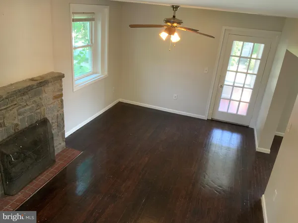 an empty room with wooden floor fireplace and windows