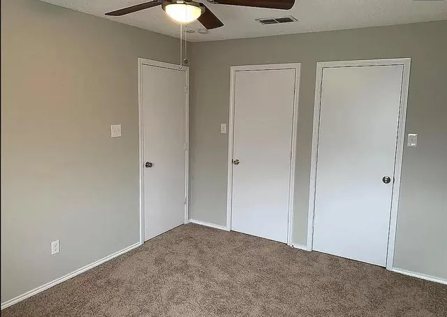 an empty room with a window and a fan