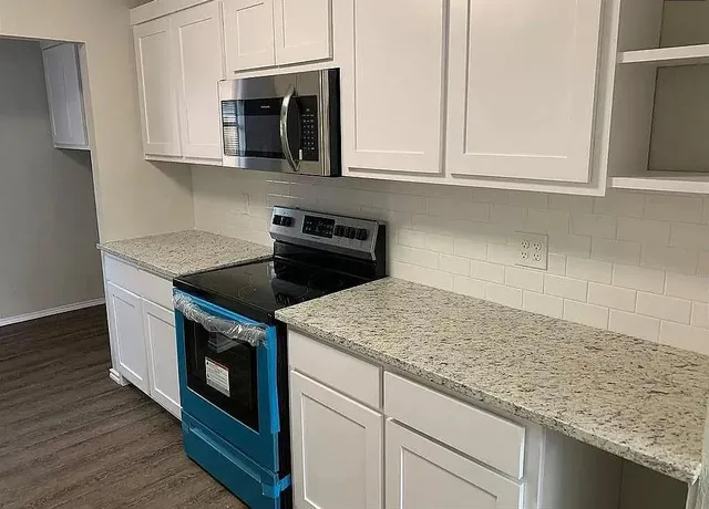 a kitchen with granite countertop white cabinets and a stove