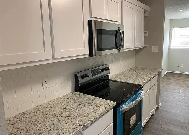a kitchen with granite countertop a stove and a microwave