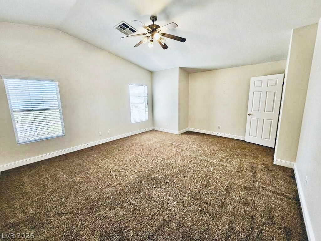 5953 Crumbling Ridge Street Henderson, NV 89011 - Photo 19 of 42 A spacious bedroom features vaulted ceilings and soft carpet underfoot, illuminated by a ceiling fan with integrated lighting.