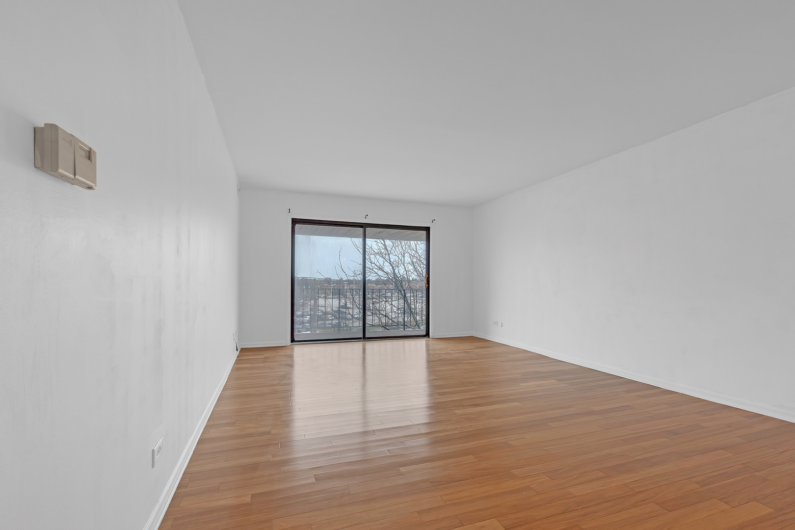 4901 Golf Road, Unit 410 Skokie, IL 60077 - Photo 5 of 26 a view of an empty room with wooden floor and a window