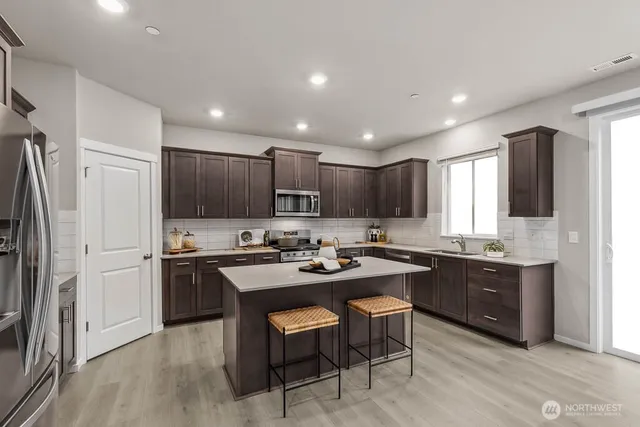 a kitchen with kitchen island granite countertop a sink stove and refrigerator