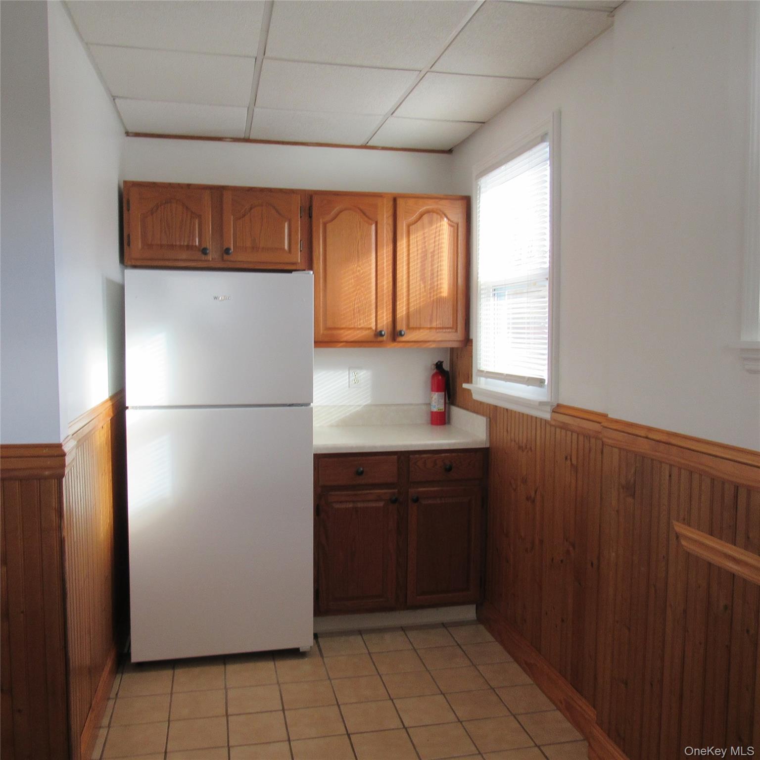 35 Taylor Avenue, Unit 2 Poughkeepsie, NY 12601 - Photo 4 of 19 Kitchen with panelled walls, freestanding refrigerator, light countertops, and brown cabinetry